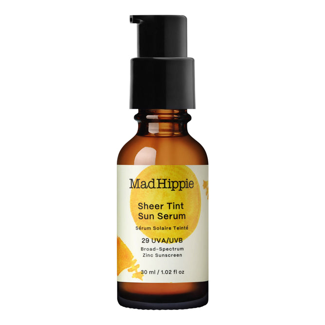 A 30 ml amber glass bottle with a black pump, labeled Mad Hippie Sheer Tint Sun Serum SPF - Light/Medium, features broad-spectrum UVA/UVB protection, Zinc SPF 29 mineral tint, and an antioxidant-boosting subtle fruit illustration.
