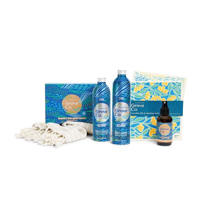 Explore Grove Collaboratives Scent Essentials - Spring Collection, a limited edition set of eco-friendly cleaning products featuring two blue bottles, a spray bottle, and floral laundry detergent sheets in a box with a folded striped cloth on a white background.
