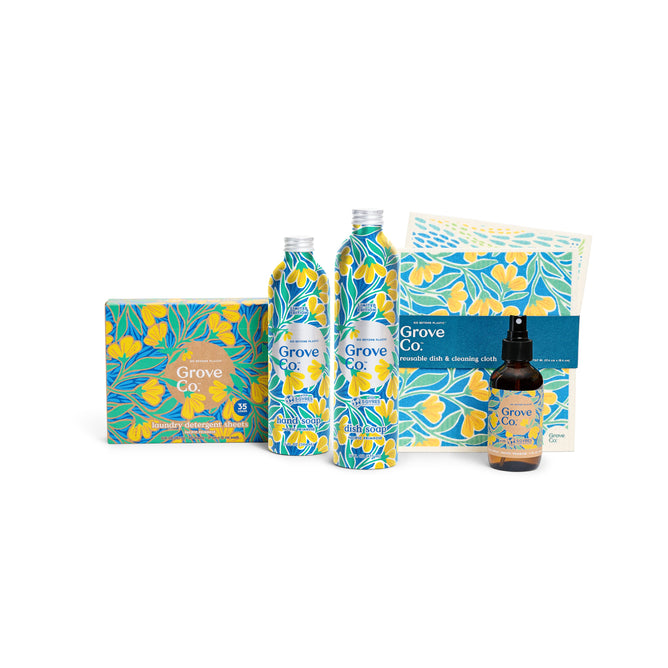 The Grove Collaboratives Spring Into Clean Set from the Spring Collection offers eco-friendly cleaning products with Pacific Primrose designs, including laundry detergent sheets, two bottles, a glass cleaner spray, and a reusable cloth with vibrant blue and yellow flowers.