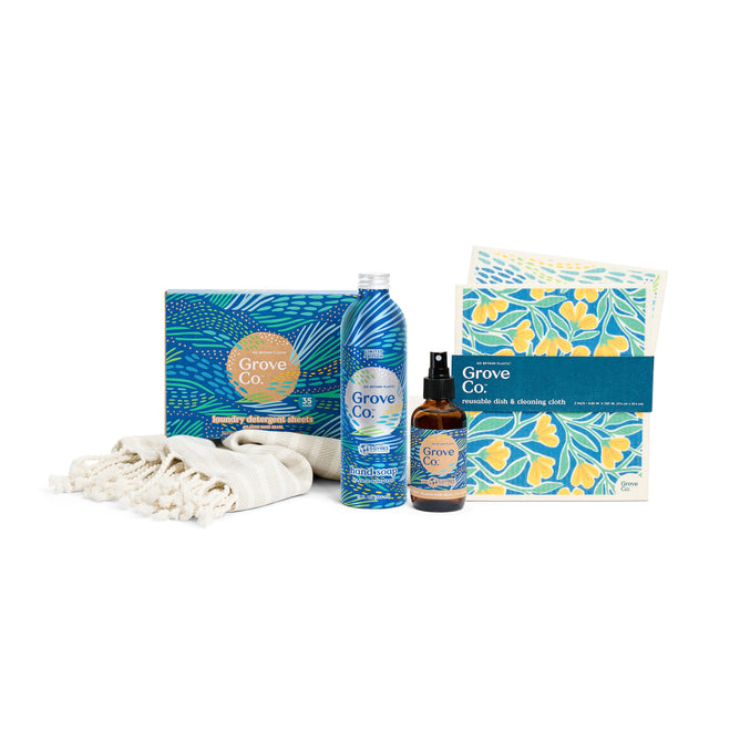 The Coastal Clean Set from Grove Collaborative’s limited edition spring collection includes a bottle, spray, reusable floral cleaning cloths, and a folded beige cloth, all elegantly displayed on a white background with vibrant packaging inspired by Atlantic Dune Grass.