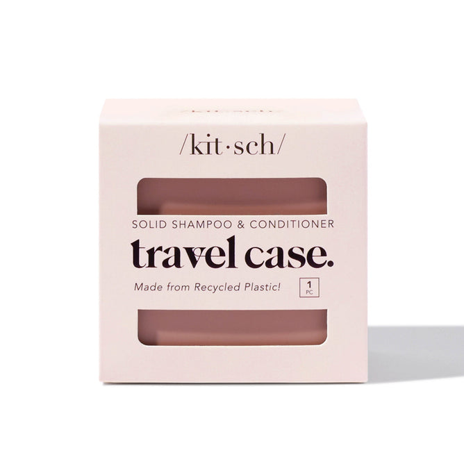 The Kitsch Bottle-Free Beauty Travel Case is a square, off-white solid shampoo and conditioner box made from recycled plastic. With black text and a clear section, it reveals the pink case inside—ideal for travel.