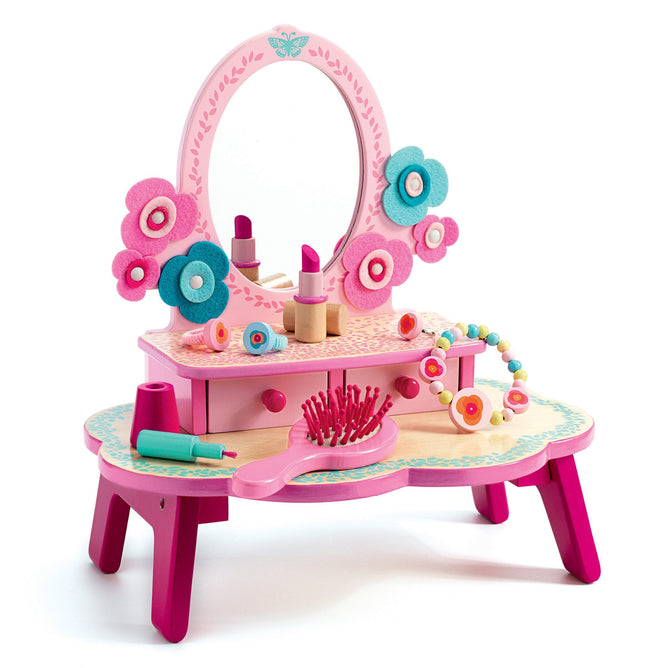 The DJECO Flora Dressing Table Play Set, made from 100% FSC® Certified Wood, features a vibrant pink and turquoise floral design with a round mirror, small drawers, a pink hairbrush, toy lipstick, and felt flower decorations crafted from non-toxic materials—ideal for imaginative play.