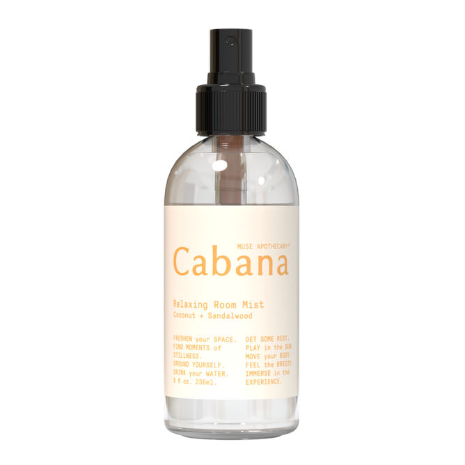 An 8 fl oz (236 ml) clear spray bottle labeled Relaxing Room Mist from Muse Apothecary, featuring a coconut and sandalwood aroma infused with essential oils. It has a black spray nozzle and a beige label that reads, Refresh your space... Feel the breeze.