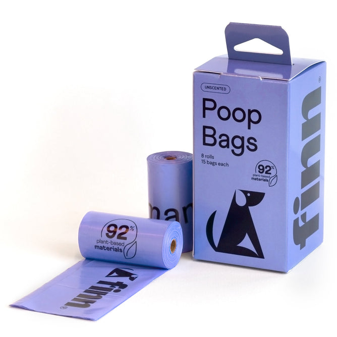 A box with Finn Poop Bags made from 92% USDA Certified Biobased Product sits beside two rolls of purple bags and an open bag. Featuring a playful dog graphic, these eco-friendly poop bags flaunt plant-based materials as sustainable pet products.