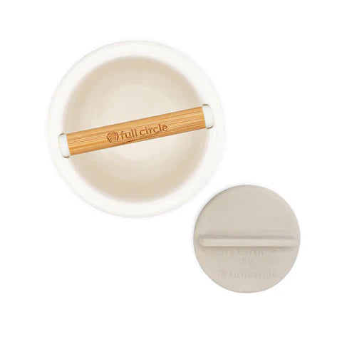 Top view of a white compost bin with a bamboo handle, featuring the Full Circle brand. A corresponding round lid, designed for easy handling and enhanced with antibacterial properties, is nearby.