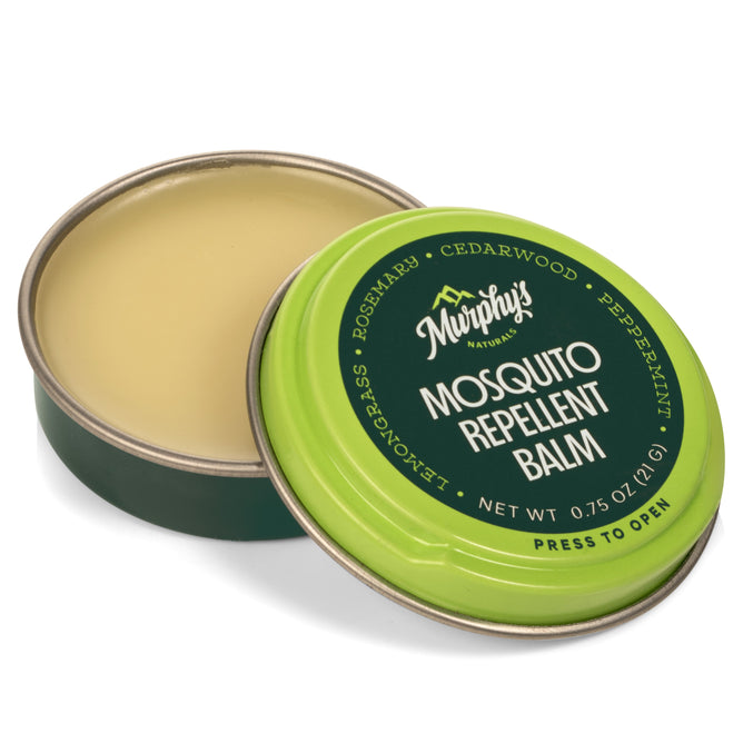 An open tin of Murphys Naturals Mosquito Repellent Balm shows a smooth cream enriched with DEET-free oils. The green lid lists ingredients: rosemary, cedarwood, peppermint, lemongrass. Net weight: 0.75 oz.