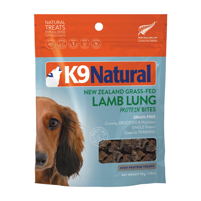 The package showcases K9 Natural Grain-Free Air-Dried Dog Treat Protein Bites made with New Zealand Grass-Fed Lamb Lung. Its in orange and blue with a dog image, offering a high-protein, nourishing treat perfect for training your pup.