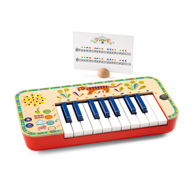 The DJECO Animambo Synthesizer is a vibrant childrens electric piano, featuring animal designs and a music sheet with notes and illustrations. Made from FSC® Certified Wood, it includes an egg-shaped wooden mallet. This non-toxic toy ensures safe playtime fun for kids.
