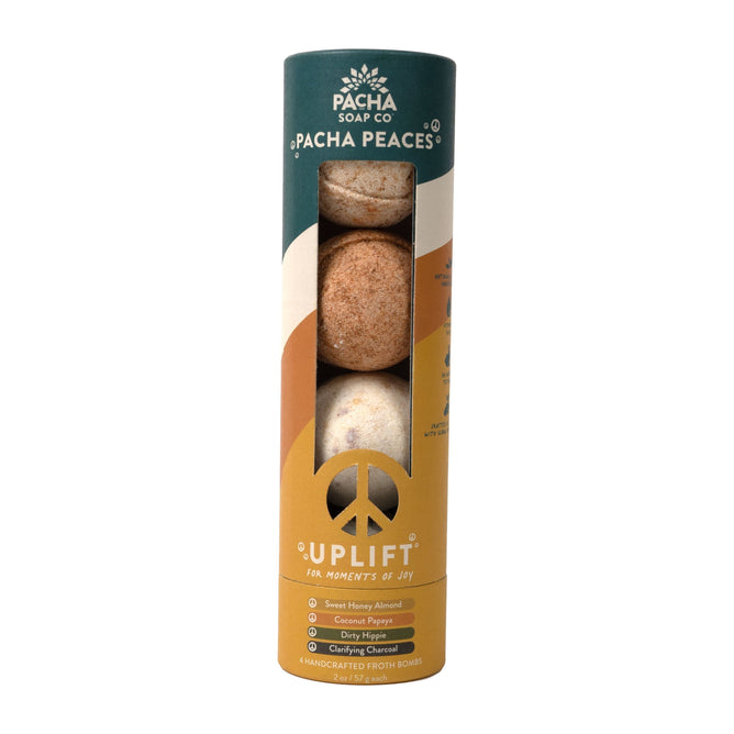 The cylindrical package of Pacha Soap Co. Froth Bomb, Pacha Peaces contains four colorful bath bombs with a peace symbol in green, orange, and white, featuring signature scents like Sweet Honey Almond and Dirty Hippie from the Calm Collection of handcrafted blends.