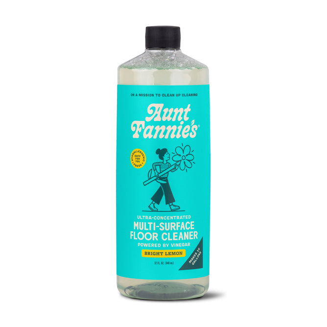 Aunt Fannies Multi-Surface Floor Cleaner in Bright Lemon features a turquoise label with white text and a black illustration of a flower-holding figure, promoting its vinegar-powered, plant-based formula for gentle, effective cleaning.