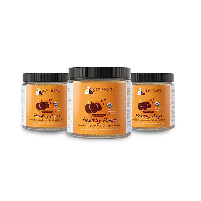 Three jars of kin+kind Healthy Poops Set digestion supplements for pets. The black-lidded jars have labels featuring pumpkins, emphasizing gut health with prebiotic fiber, in orange and black text.