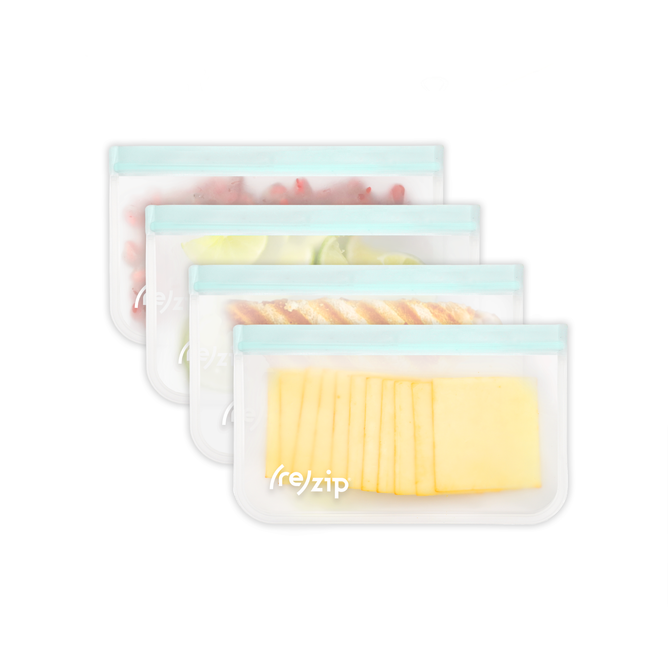 Four Flat Half Gallon (Deli) Bags by (re)zip, featuring durable, transparent zip-tops with light blue sealing strips, neatly hold sliced cheese, bread, limes, and berries for perfect fridge organization!.