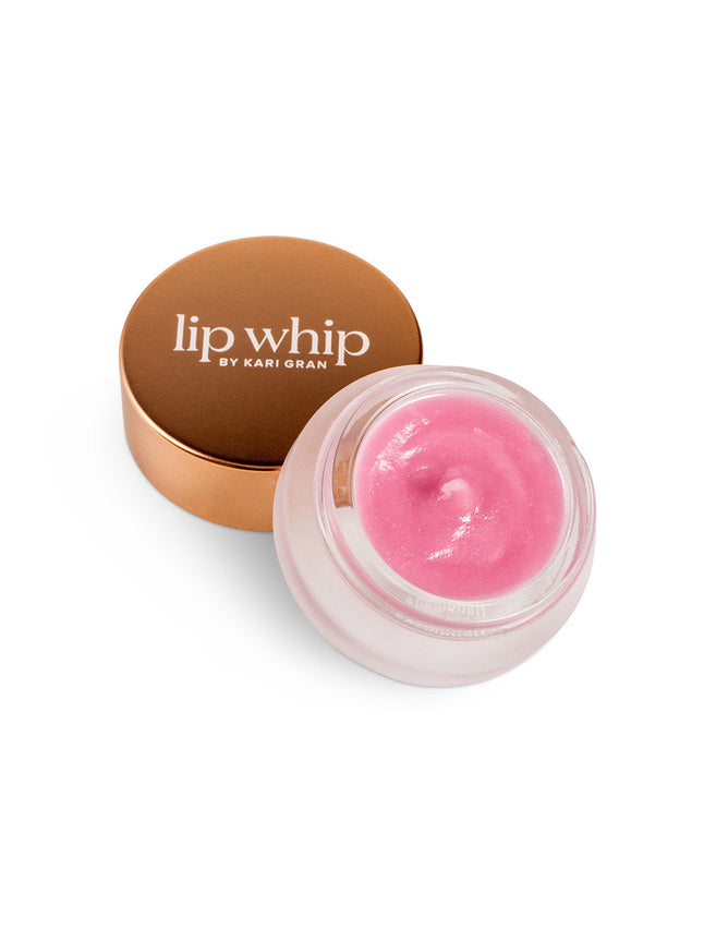 A small glass jar of Kari Grans Peppermint Lip Whip Treatment Balm, a natural lip care essential, showcases a gold lid slightly open to reveal the smooth pink balm inside, set elegantly against a white backdrop.