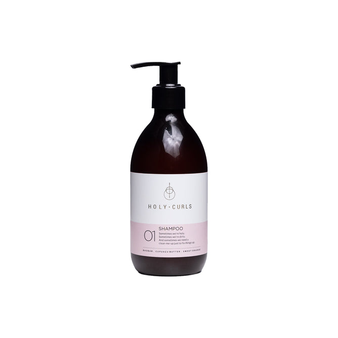 A black pump dispenser tops this dark brown bottle labeled Holy Curls Shampoo 01. Infused with nourishing baobab oil, it features a sulfate-free formula with a white and light pink label, set against a plain white background.