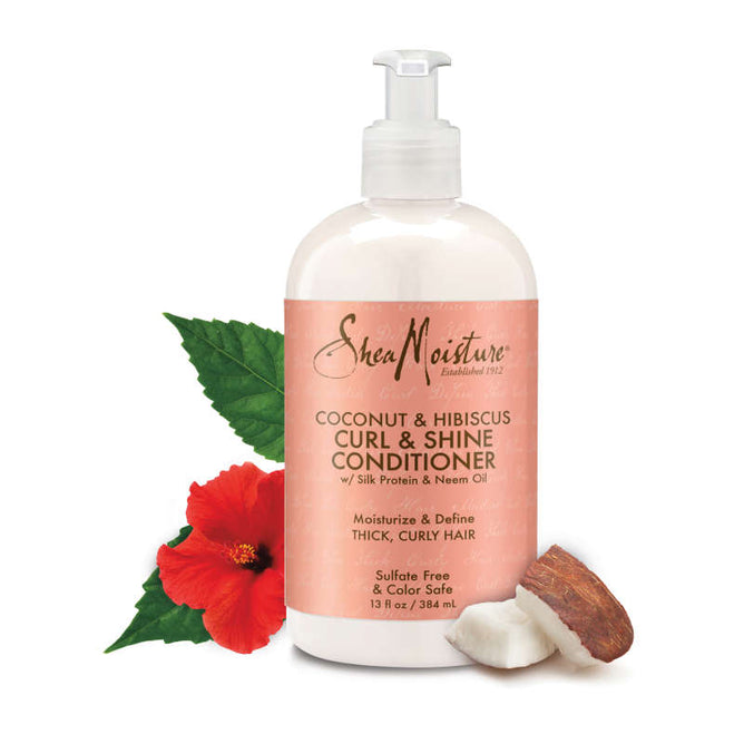 A bottle of SheaMoistures Coconut + Hibiscus Curl & Shine Conditioner features a pump dispenser, highlighting silk protein and neem oil on its label, along with a red hibiscus flower, green leaves, and a piece of coconut.