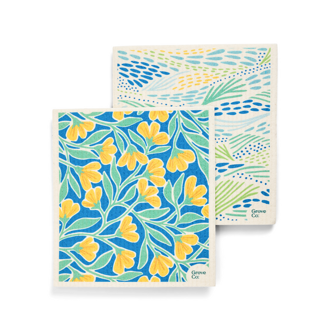 The Grove Co. Swedish Dishcloth - Spring Collection includes two patterned cloths: one with a blue backdrop adorned by yellow flowers and green leaves, and another with an abstract blue and green line pattern on white. These reusable, eco-friendly cloths help reduce plastic pollution.