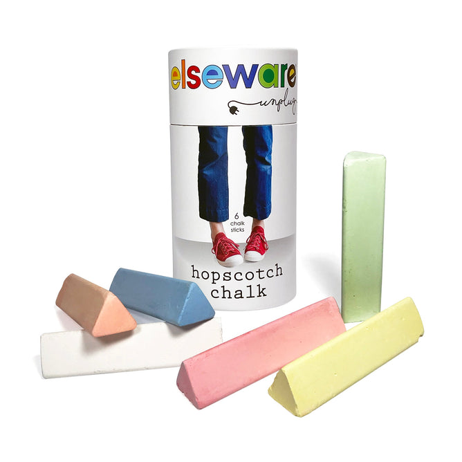 The Elseware Unplug Hopscotch Chalk comes in a cylindrical container with an image of legs in jeans and red sneakers. Six non-toxic pastel chalk sticks (pink, green, yellow, blue, white, peach) are scattered in front to inspire physical activity and creativity.