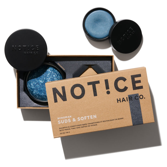 The image displays two round containers of solid blue shampoo bars by NOT!CE Hair Co., in an open box labeled Wingman Travel Set, designed to hydrate and promote strong hair growth.