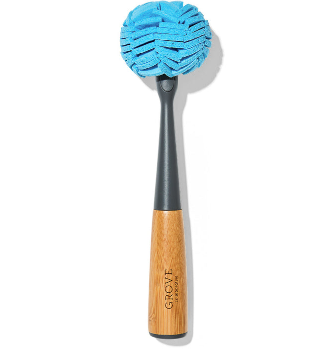 The Glassware Cleaner Replacement Head by Grove Co. is a cleaning brush with a long handle and a round, textured blue sponge, ideal for removing lipstick stains. The handle has parts made from wood and showcases the Grove brand on its plain white background.