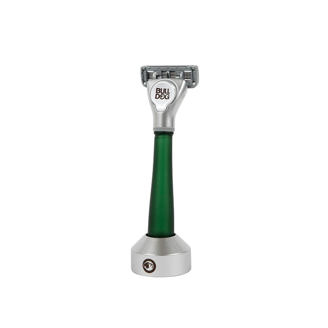 The Bulldog Recycled Glass Handle Razor with Razor Stand boasts a sleek silver multi-blade head and green handle, offering a comfortable shave. Its design allows it to stand upright, displaying the BULLDOG branding on the head.