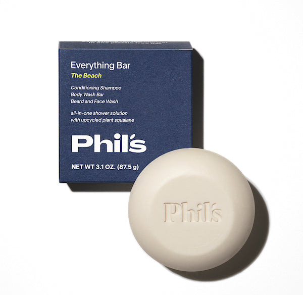 A round 3.1 oz (87.5 g) bar of Phils Everything Bar, enhanced with chia seed oil, serves as a conditioning shampoo, body wash bar, and face wash—all in one. Its packaged in a blue box labeled The Beach.