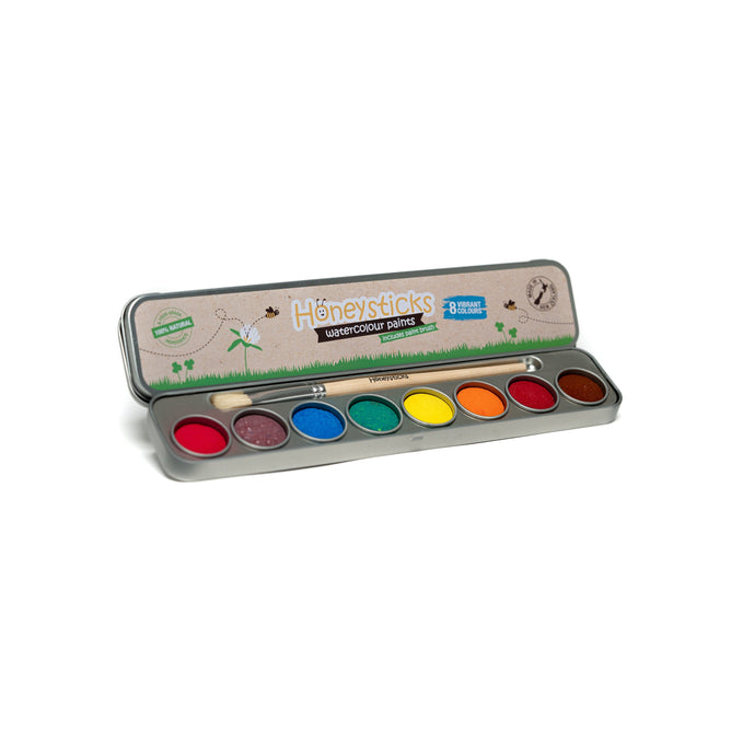 A tin case of Honeysticks Watercolor Paints displays eight vibrant, non-toxic colors: red, purple, blue, green, yellow, orange, and brown. This eco-friendly gift set features playful illustrations perfect for creative expression.