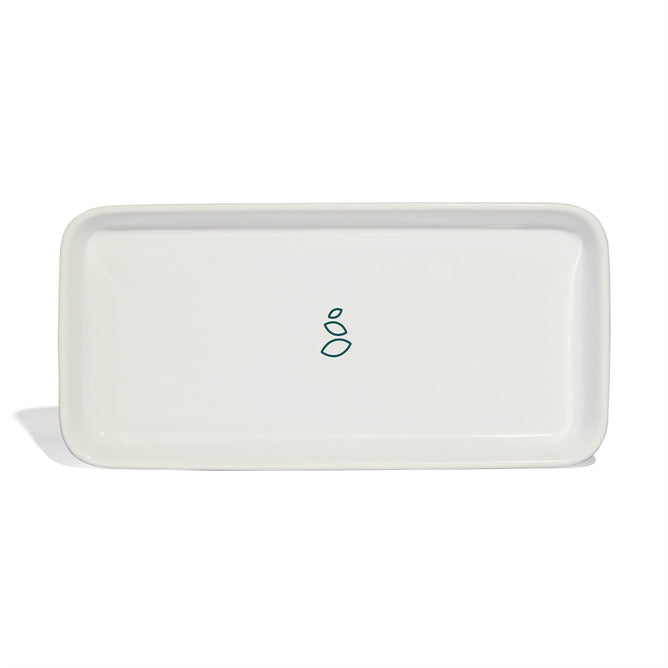 The Grove Co. Ceramic Sink-Side Tray is a rectangular white ceramic tray featuring rounded corners and a simple green abstract design at the center, making it an ideal stylish addition to your kitchen accessories.