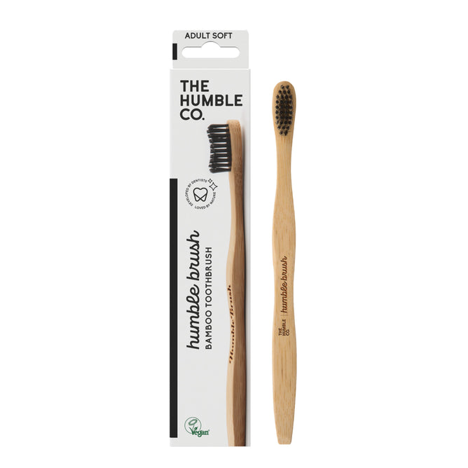 The Adult Bamboo Toothbrush - Soft from The Humble Co. features dentist-approved black nylon bristles and is elegantly presented in a white box with green and black text displaying the logo and the soft designation.