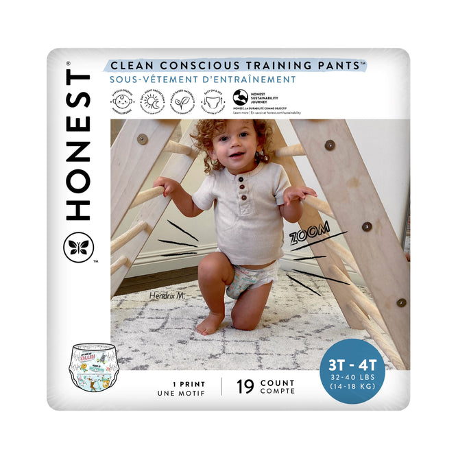 A toddler playfully stands in a wooden structure, wearing The Honest Companys Training Pants - 3T/4T. These training pants are ideal for potty-training with an absorbent core and come in a 19-count pack for children weighing 32-40 lbs. Clean Conscious Training Pants is prominently displayed on the packaging.