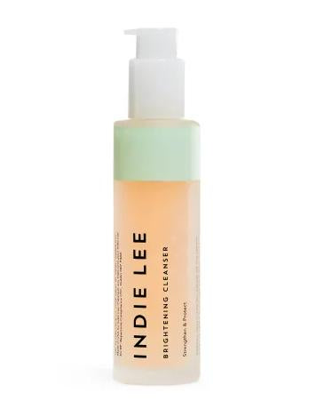An Indie Lee Brightening Cleanser bottle with a pump features antioxidant-rich peachy-orange liquid. It has a clear design, a green label on top, and black text on the body.