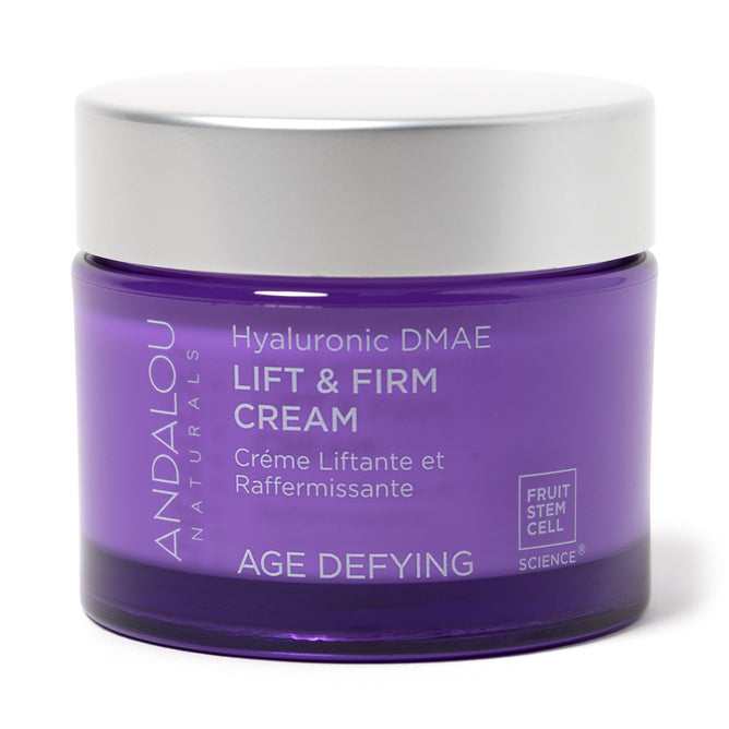 A jar of Andalou Naturals Age Defying Hyaluronic DMAE Lift & Firm Cream features a purple body with a white lid. The label boasts Crème Liftante et Raffermissante with fruit stem cell complex technology, highlighting its cruelty-free skincare benefits.