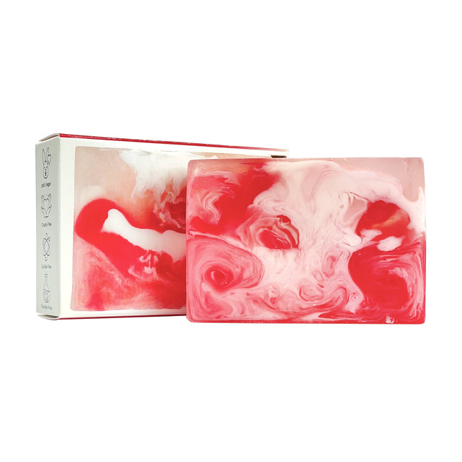 The Blooming Rose Soap Bar by Soapymania, a rectangular handcrafted soap with red, pink, and white swirls, stands before a white box featuring matching design elements and minimalistic icons that emphasize its soothing and moisturizing qualities.