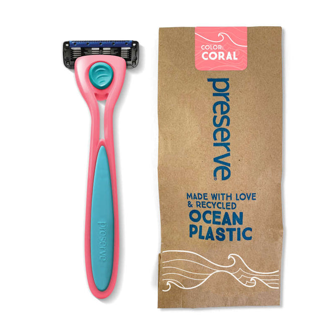 A coral and blue Preserve Recycled Ocean Plastic (POPi) Shave 5 Razor System with an ergonomic handle lies next to its brown packaging, showcasing an ocean waves design and emphasizing its sustainable creation from recycled ocean plastic.