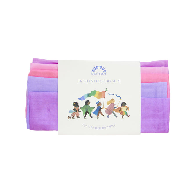 A package of Enchanted Playsilk for Open-Ended, Imaginative Play by Sarahs Silks is crafted from luxurious mulberry silk, featuring a vibrant illustration of children playing. The elegantly folded silk reveals enchanting pink, purple, and blue shades.