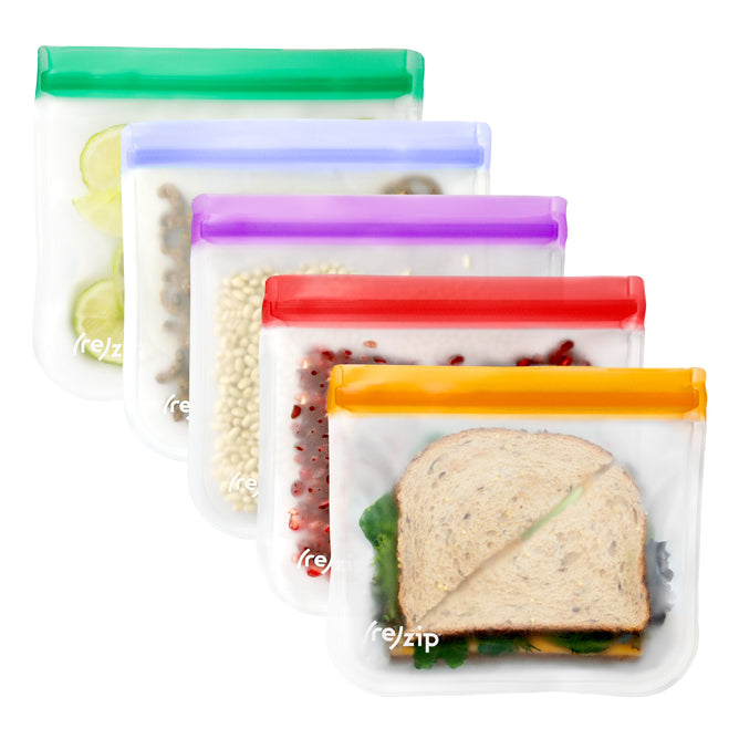 Five (re)zip Flat Lunch Bags (VIP Discount) are lined up diagonally, each with a different colored seal. Made from BPA-free PEVA, these leakproof bags hold cucumbers, nuts, beans, berries, and sandwiches.