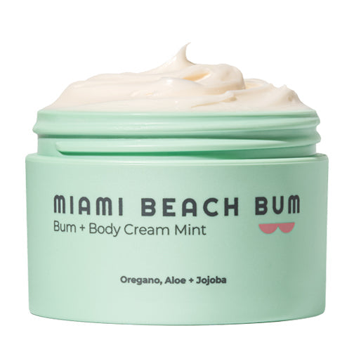 The Miami Beach Bum Bum + Body Cream jar in light green, with its lid off, showcases a creamy texture. The label features key ingredients like oregano, aloe, and jojoba—ideal for promoting skin health by combating body acne and nourishing skin.