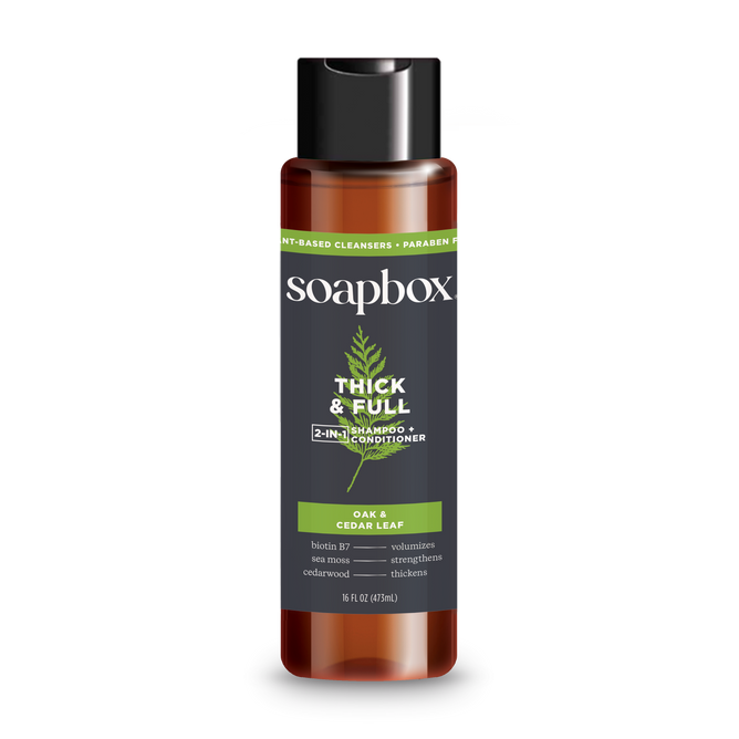 The Soapbox Thick & Full 2-in-1 Shampoo & Conditioner, infused with oak, cedar leaf, and biotin B7, volumizes and strengthens hair for a fuller look. Its packaged in a brown bottle with a black cap and green label accents.