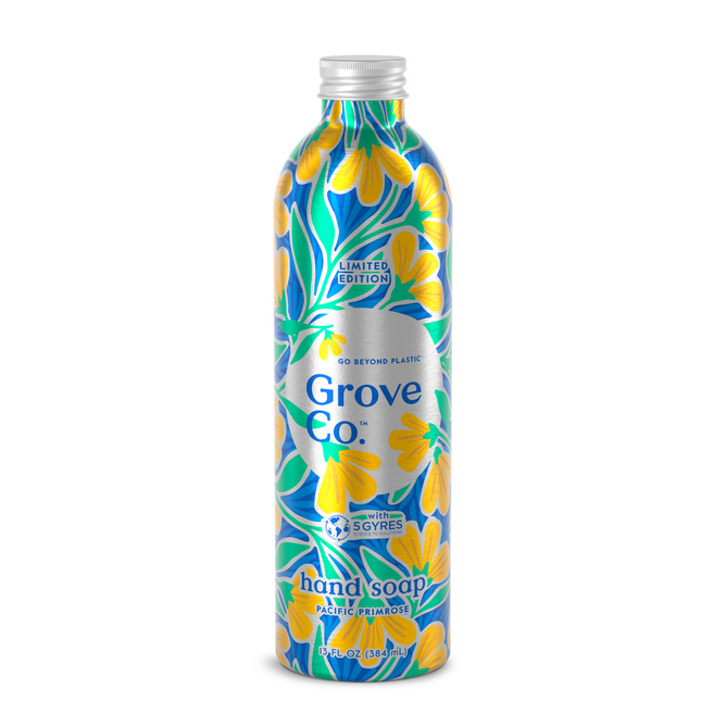A metal bottle of Grove Co. hand soap refill from the Spring Collection showcases a vibrant floral design with yellow and blue flowers on a dark background. The Pacific Pompia label emphasizes its eco-friendly approach against plastic pollution in marine ecosystems.