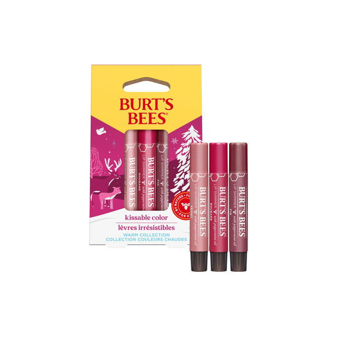 Burts Bees Kissable Color Warm Lip Shimmer set includes three Shea Butter-infused, 100% natural lip tints from the Warm Collection. The festive packaging features winter trees and a reindeer, highlighting shades of red and pink.