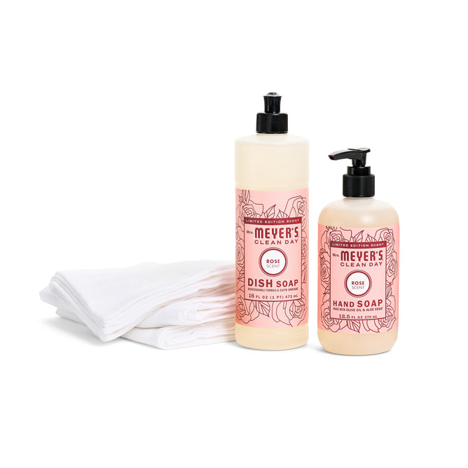 Mrs. Meyers Spring Scent Essentials, featuring dish and hand soaps with a refreshing rose scent, are set next to eco-friendly white cloths.