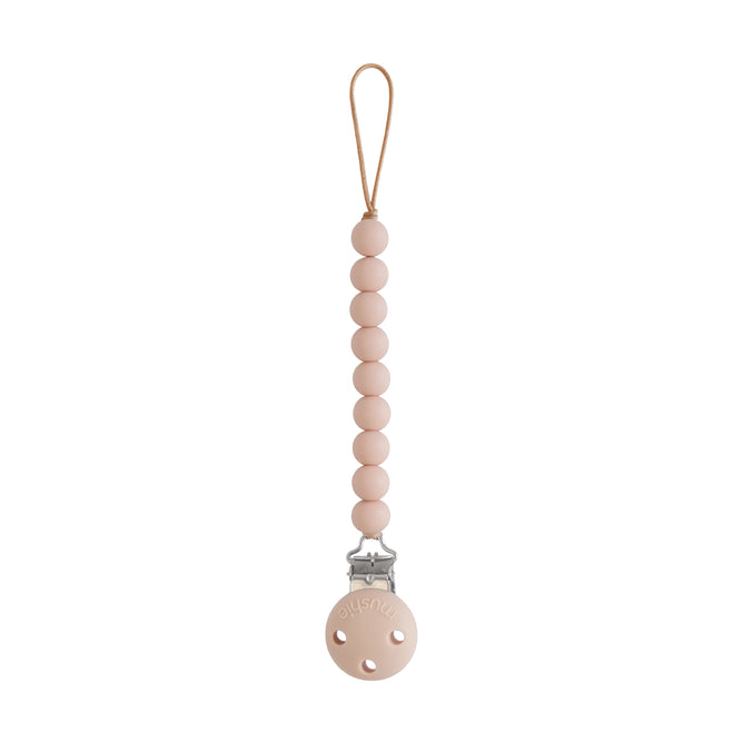 The mushie Silicone Pacifier Clip | Hera in beige is made from food-grade silicone with round beads, a top loop for pacifier attachment, and a metal clip to secure to clothing—an essential for your baby essentials.