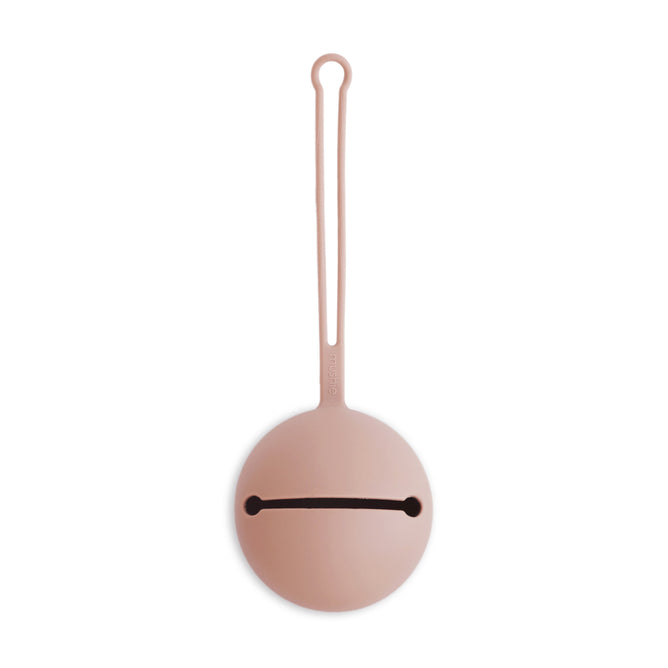 The mushie Silicone Pacifier Holder Case is a round, light pink food-grade silicone case with a long loop handle and horizontal slit opening, perfect for holding and carrying small baby essentials.