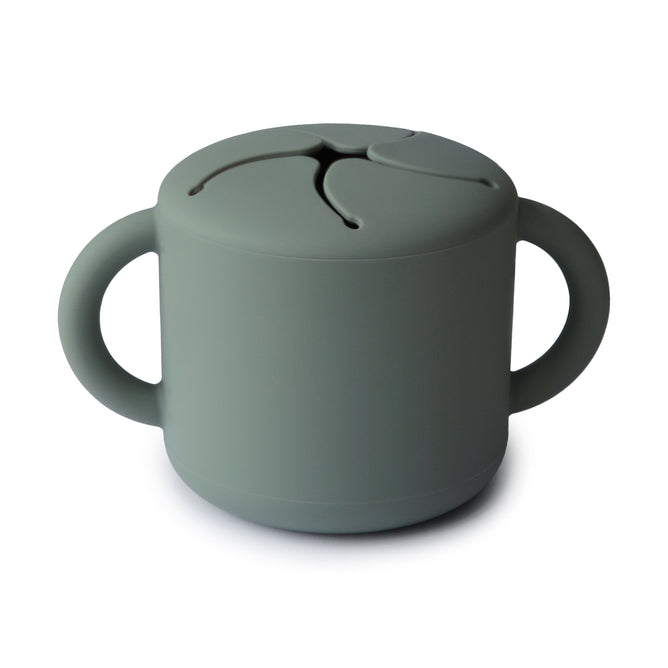 The mushie Silicone Snack Cup – Easy-Grip Handles, BPA-Free is a gray-green food-grade silicone cup with two handles and a flexible, slotted lid for easy snack access and spill prevention—perfect among baby essentials.