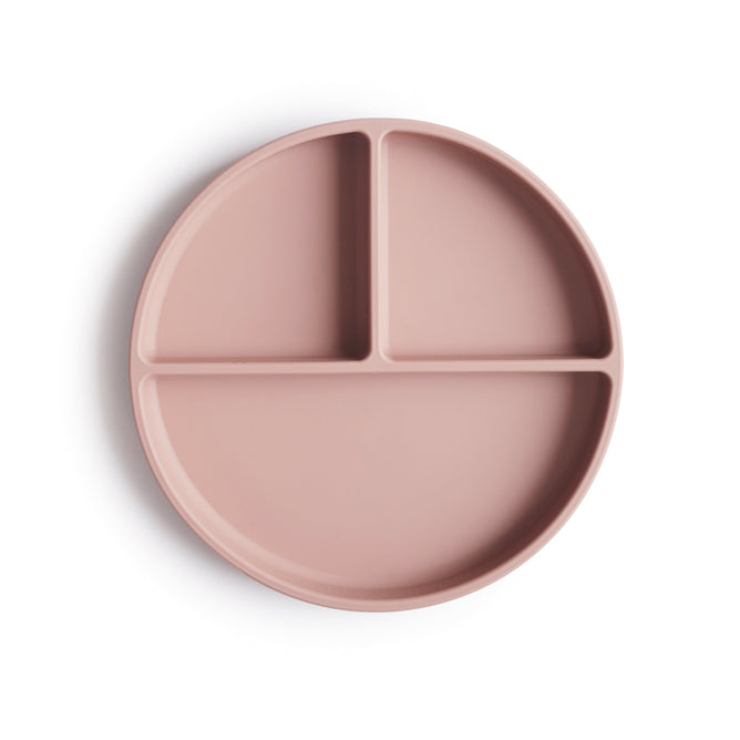 The mushie Silicone Suction Plate is a round, light mauve, food-grade silicone plate with three compartments—one large, two small. Safe, non-toxic, and BPA-free; photographed on a white background.