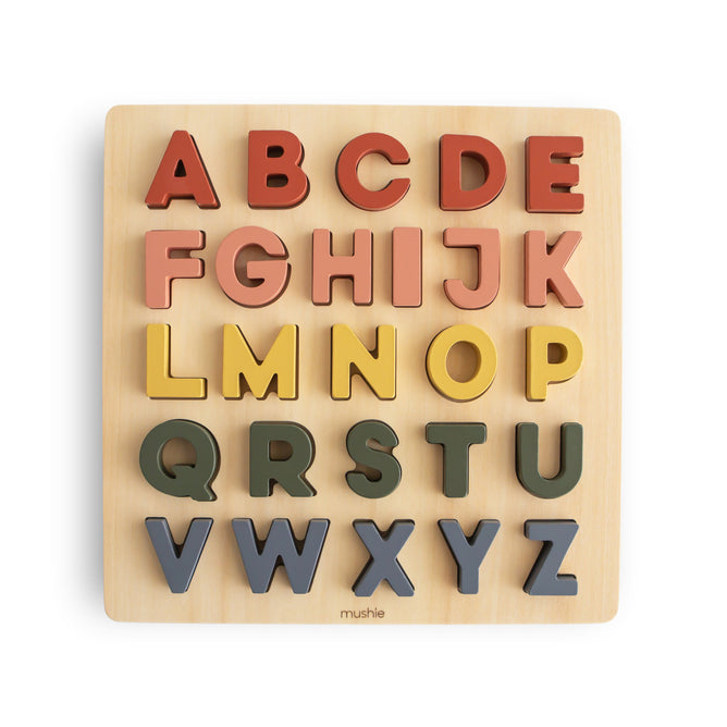 The mushie Wooden Alphabet Puzzle – FSC Certified Wood features colorful, chunky uppercase letters in four rows on a light wood board—perfect for building fine motor skills and learning the alphabet.