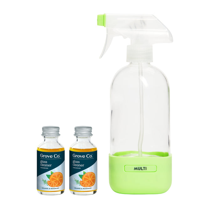 Two small bottles labeled Glass Cleaner Concentrate Starter Set with Orange & Rosemary illustrations sit beside an empty Reusable Cleaning Glass Spray Bottle with a green base, all under the Grove Co. brand.