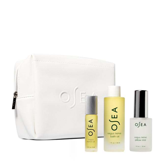 The Vagus Nerve Travel Set by OSEA includes a white toiletry bag embossed with OSEA and features a small bath oil, soothing vagus nerve bath oil, and calming vagus nerve pillow mist, ideal for wellness travel.