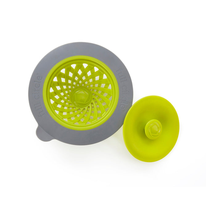 The Sinksational Sink Strainer by Full Circle comes in gray and green, made from recycled plastic. It features a circular grid-patterned strainer and a dome-shaped, flat-bottomed stopper. Both pieces elegantly sit against a white background, highlighting their eco-friendly craftsmanship.