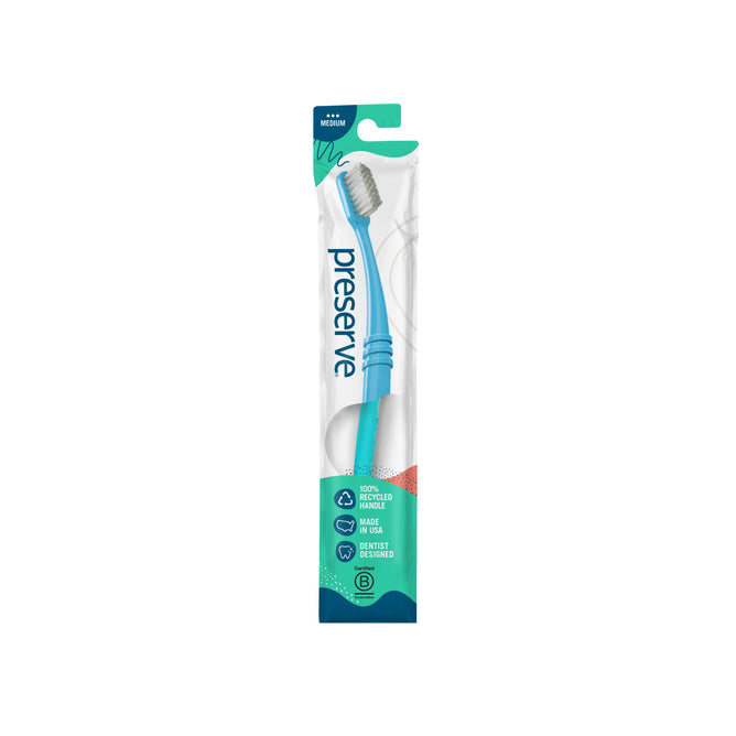 A Preserve Medium Toothbrush in eco-friendly packaging, made from recycled plastic with a curved handle. The blue toothbrush highlights its medium bristles and commitment to sustainable oral care.