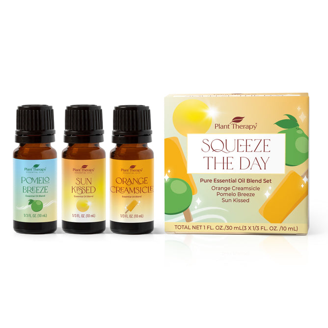 Plant Therapys Squeeze the Day Essential Oil Blend Set includes three amber bottles labeled Pomelo Breeze, Sun Kissed, and Orange Creamsicle. Nestled beside a yellow box adorned with citrus and popsicle illustrations, these invigorating aromas invite you to embrace the day.